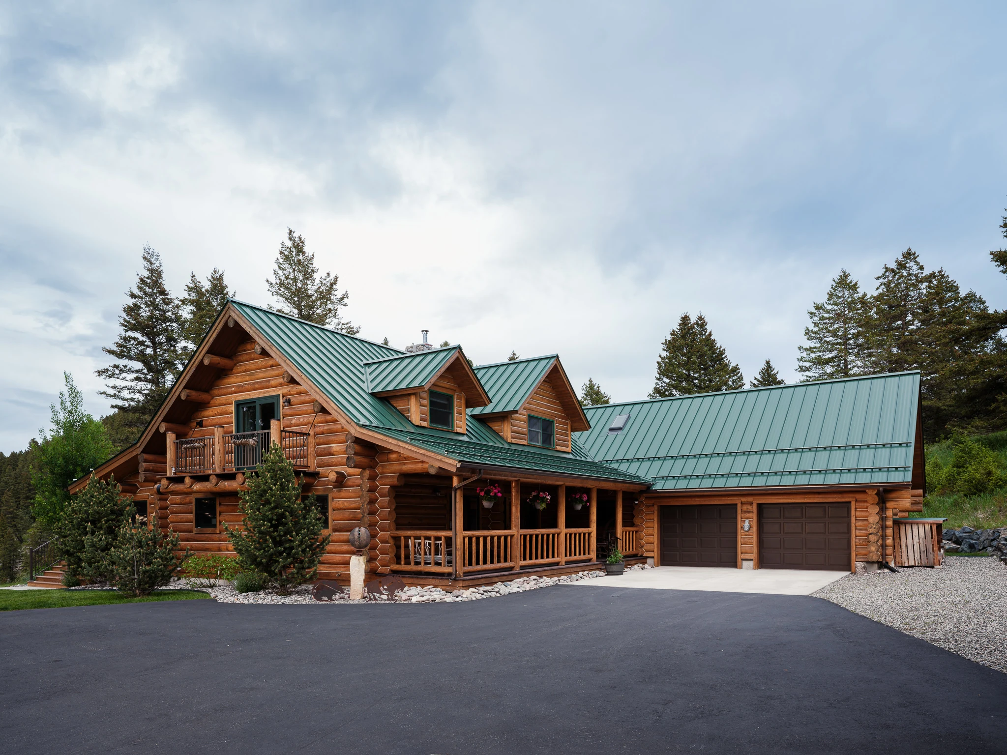 Log home exterior with a green metal roof and covered porch — architectural photography Livingston Montana, Sam Schlauch Designs
